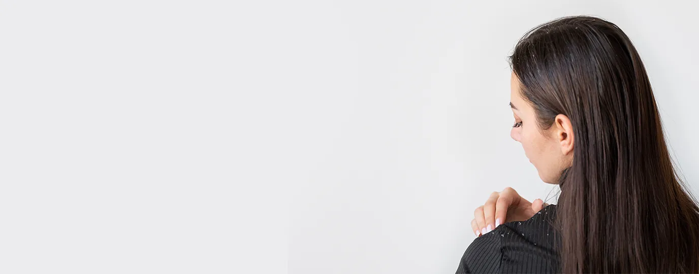 Woman looking at white dandruff flakes on her black shirt 1376x540