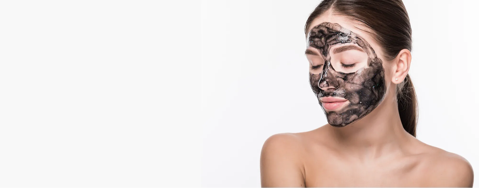 Woman with a black peel treatment mask on her face for skin exfoliation and deep pore cleansing at Dermatrix clinic 2000x785