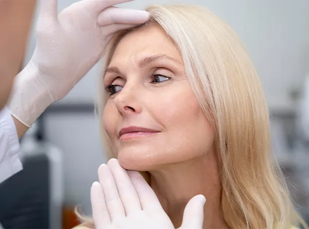 Medical professional examining woman's facial skin for common aging concerns like wrinkles and sagging skin 620x460