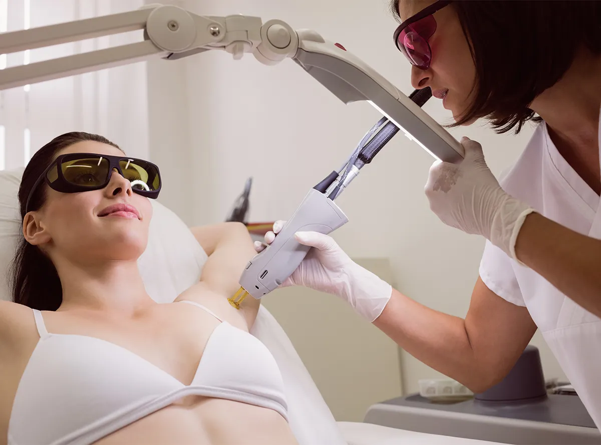 A woman receiving professional underarm laser hair removal treatment from a technician in a dermatrix clinic 1200x890