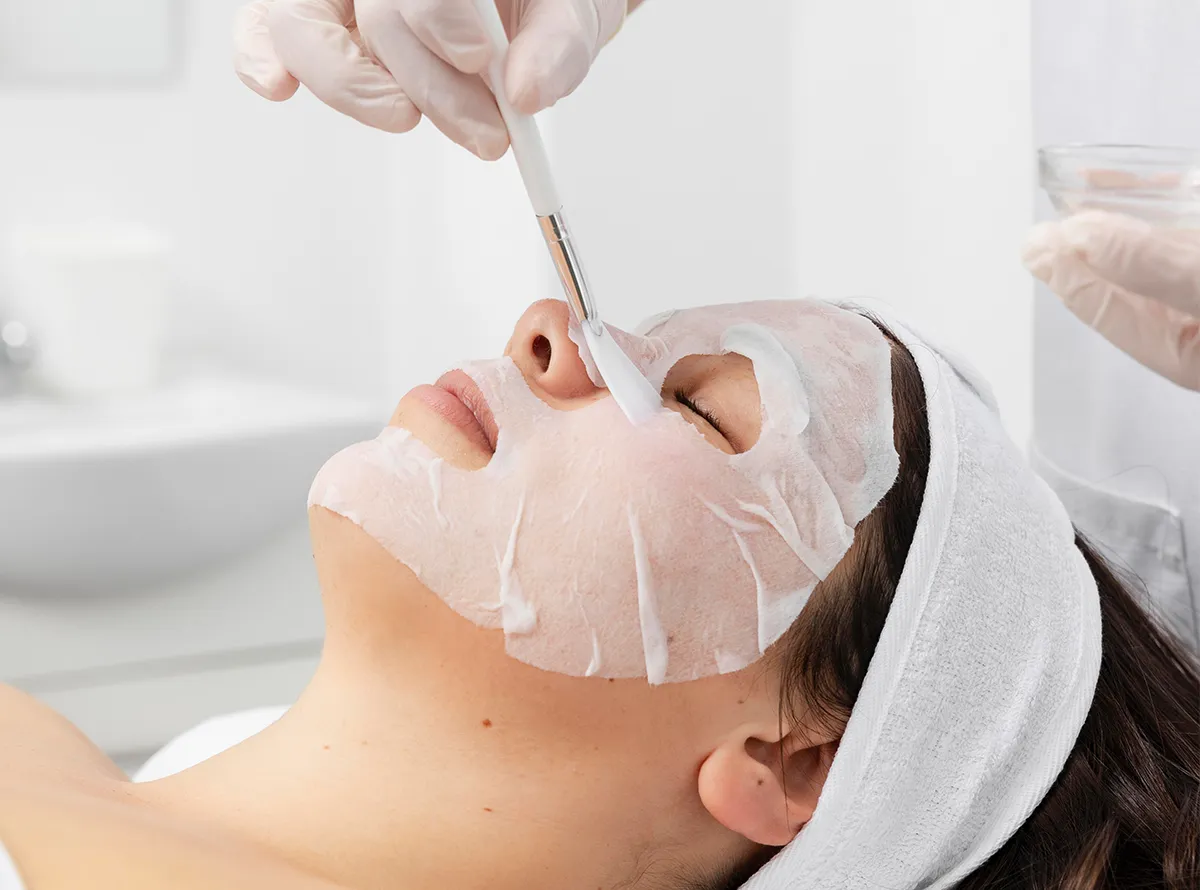 Esthetician applying a hydrating sheet mask during a signature facial treatment 1200x890